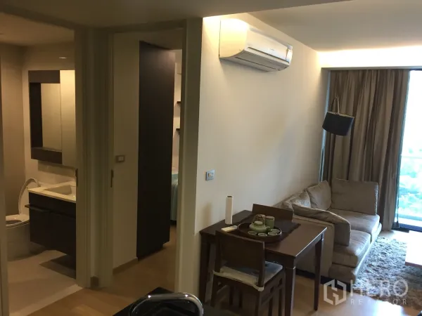 Condominium for rent or sale in Watthana, Bangkok - Cozy living and dining area with sofa, dining table, air-conditioning, and access to the bedroom and bathroom.