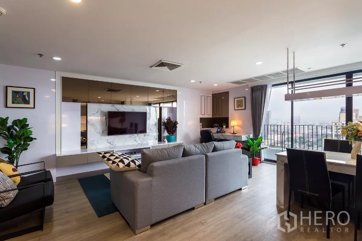 Condominium for rent or sale in Watthana, Bangkok - Living and dining space opening to a balcony with floor-to-ceiling windows and skyline views.