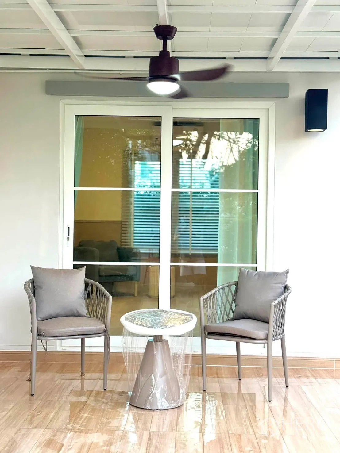 Detached House for rent in Bang Phli, Samut Prakan - Close-up of patio seating for two under a ceiling fan beside sliding glass doors.