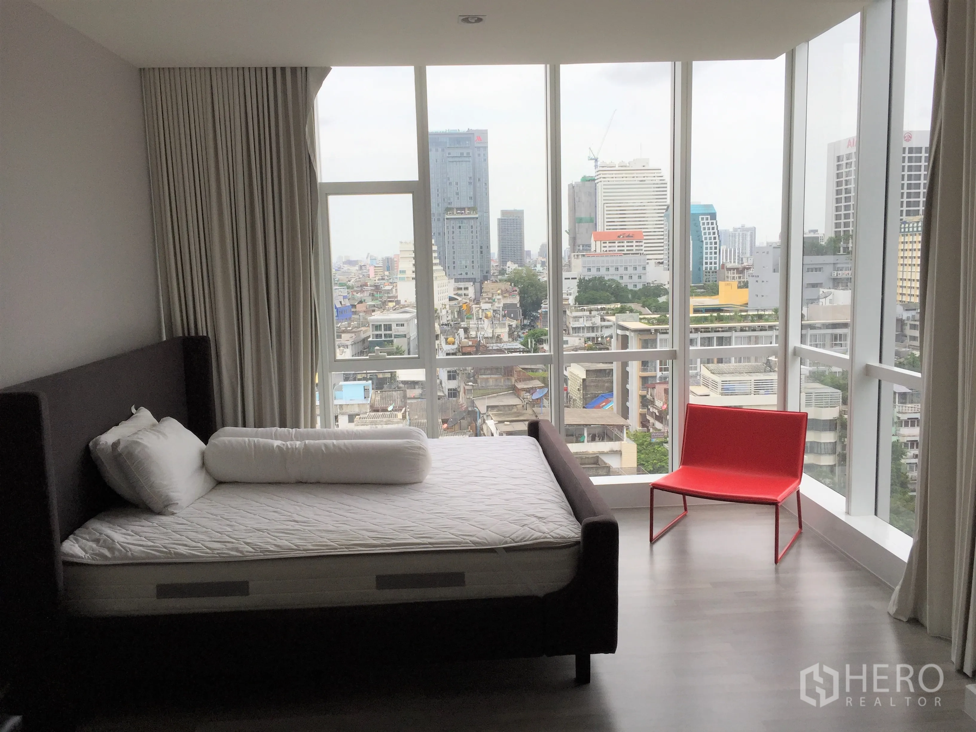 Condominium for rent in Bang Rak, Bangkok - Corner bedroom with panoramic floor-to-ceiling windows overlooking the Silom skyline.