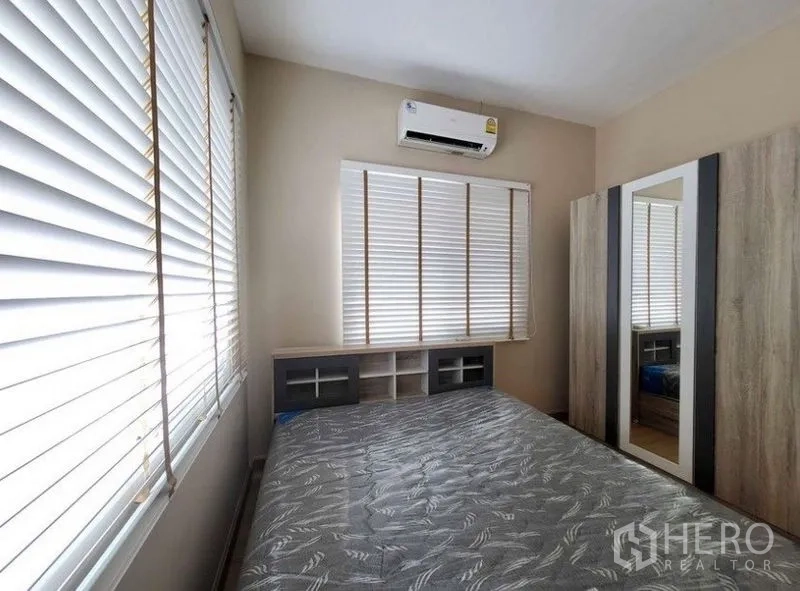 Townhouse for rent or sale - Cozy second bedroom featuring window blinds, air conditioner, mirrored wardrobe and bedside storage.
