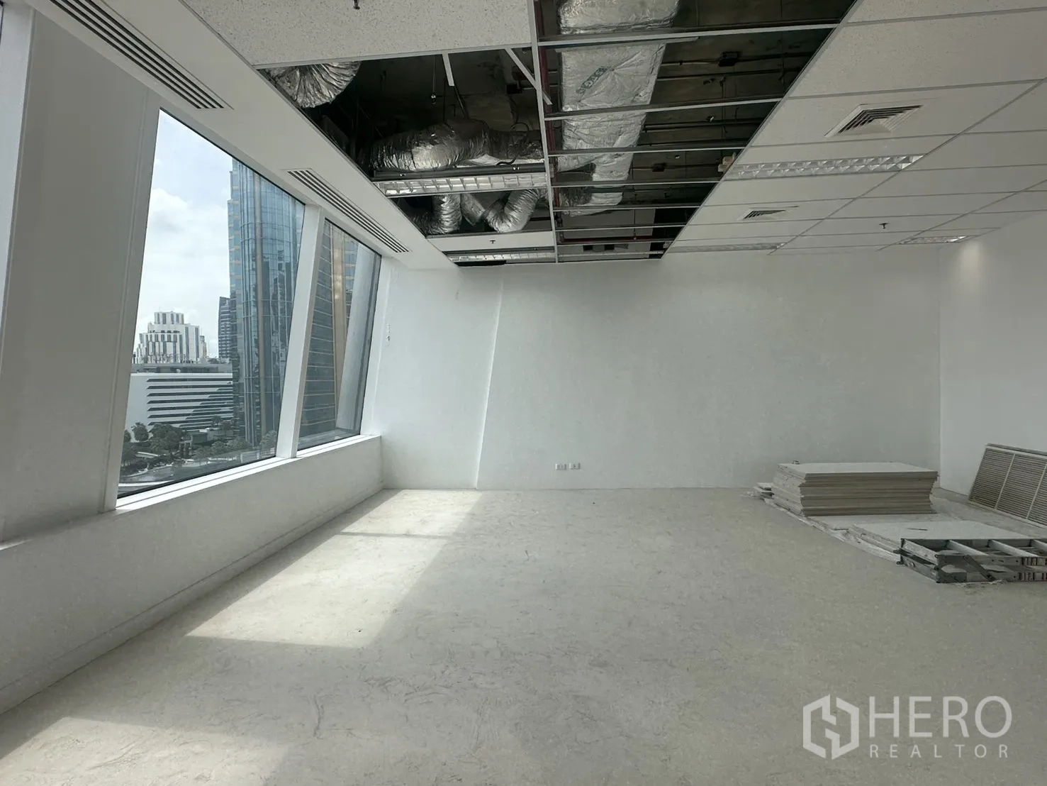 Office Space for rent in Watthana, Bangkok - Sunlit section with exposed ceiling services and stacked panels on the floor.