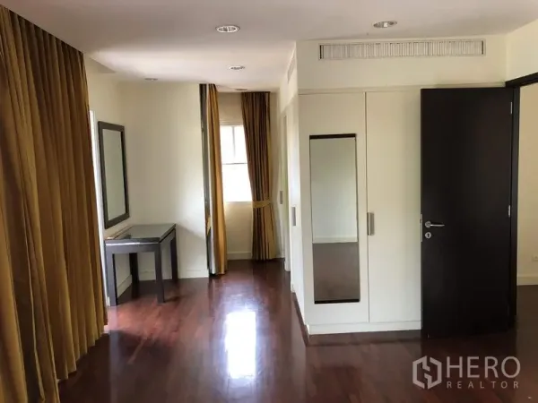 Detached House for sale in Wang Thonglang, Bangkok - Upper-floor bedroom featuring wood flooring, built-in wardrobe, and a dressing nook with desk.