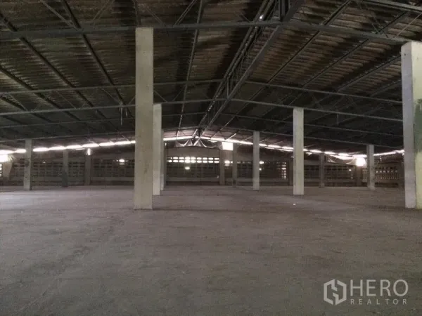 Warehouse for rent in Samut Prakan - Spacious warehouse interior with concrete floor, steel trusses and support columns.