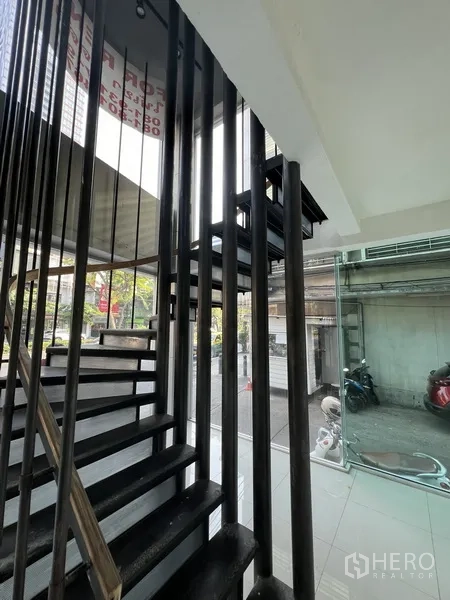 零售空间 出租在Bang Rak, Bangkok - 金属楼梯，黑色竖向栏杆，旁为通高玻璃墙。