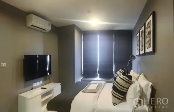 Condominium for sale in Khlong Toei, Bangkok - Bedroom with double bed, TV, air conditioner and blackout blinds.