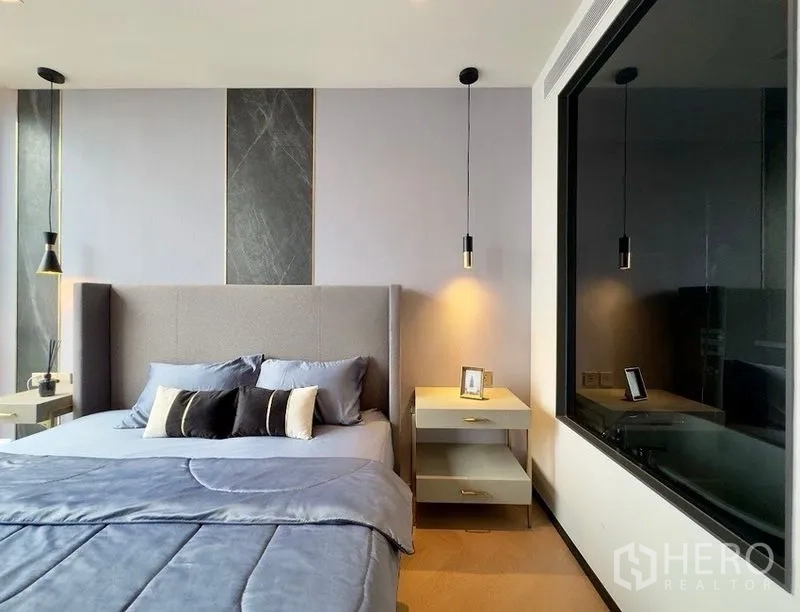 Condominium for rent or sale in Watthana, Bangkok - Cozy bedroom with pendant lamps, side tables, and a large interior window to the bathroom.