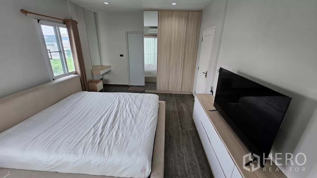 Detached House for rent in Khlong Toei, Bangkok - Primary bedroom facing TV console and built-in wardrobe with wood flooring.