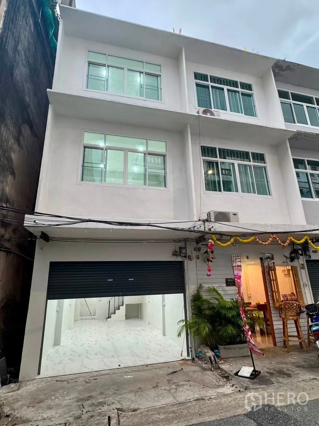 店屋 for rent in Sathon, Bangkok - 三层白色商住楼外观，宽幅卷闸门与大窗户。