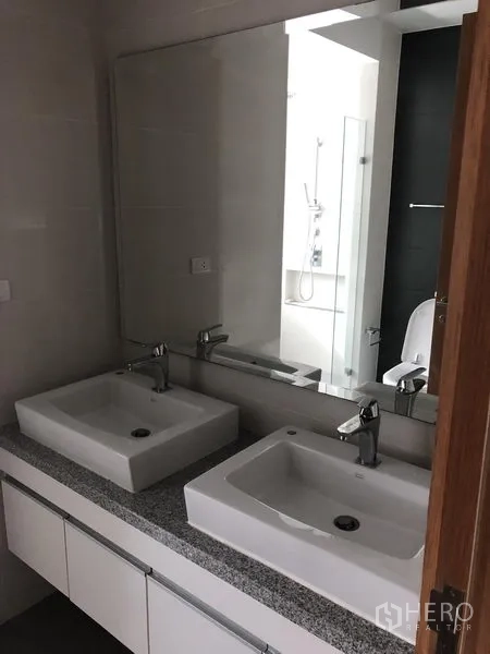Condominium for rent in Khlong Toei, Bangkok - Double vanity bathroom featuring twin square basins and a large mirror.