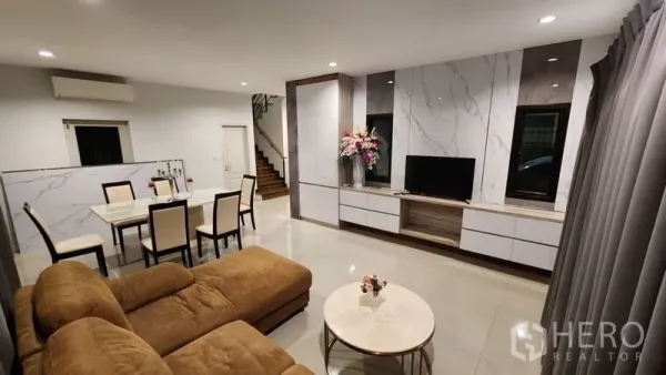 独立式住宅 出租在Prawet, Bangkok - 开放式客餐厅，转角沙发、电视墙与楼梯。