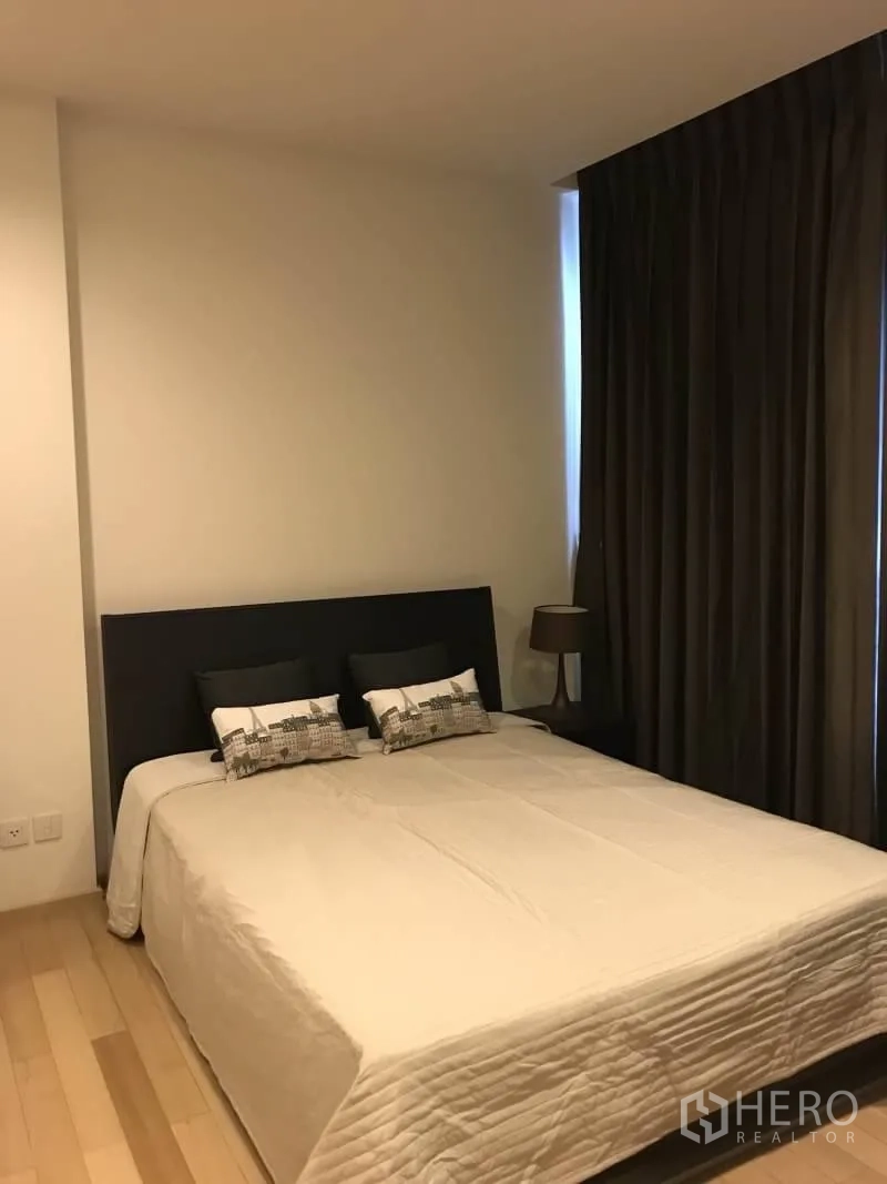 公寓 出租在Khlong Toei, Bangkok - 舒适卧室，配大床、遮光窗帘、床头灯与木地板。
