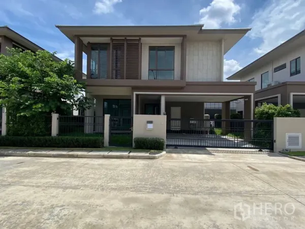 Detached House for rent in Bang Kapi, Bangkok - Modern two-storey detached house with gated carport in Hua Mak, Bang Kapi under a blue sky.