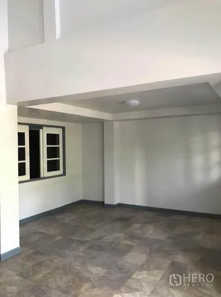 Townhouse for rent in Suan Luang, Bangkok - Open ground-floor living area with tiled flooring, white walls and a recessed ceiling.