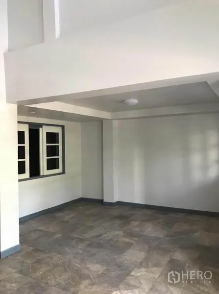 Townhouse for rent in Suan Luang, Bangkok - Open ground-floor living area with tiled flooring, white walls and a recessed ceiling.