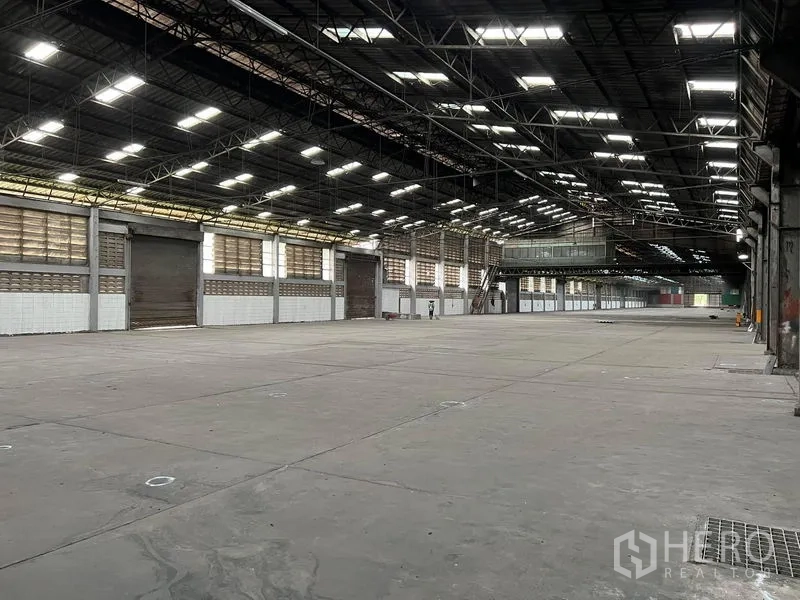 Warehouse for rent in Bang Pa-in, Phra Nakhon Si Ayutthaya - Interior view showing multiple roller doors, an overhead steel structure and bright lighting.