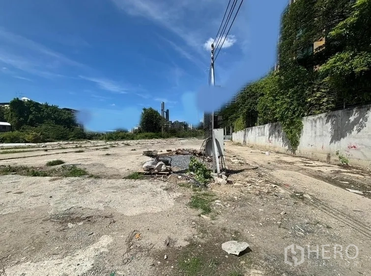 Land for rent in Khlong Toei, Bangkok - Cleared land plot with concrete base, power pole and walled boundary under blue sky in Ekkamai.