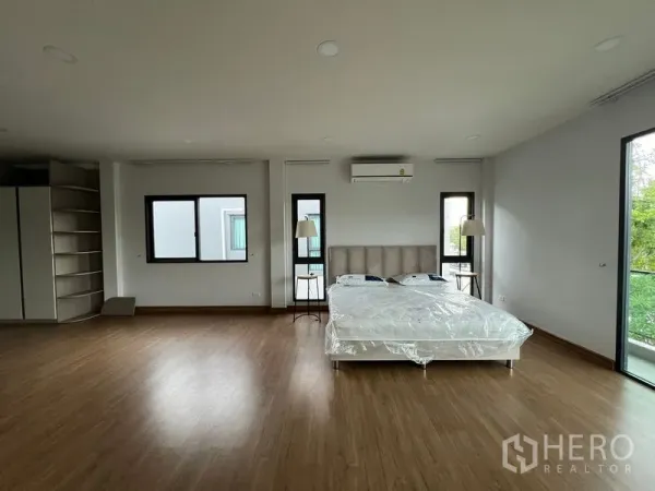 Detached House for rent or sale in Bang Phli, Samut Prakan - Spacious master bedroom with large windows, king bed, wood floors and air conditioning.
