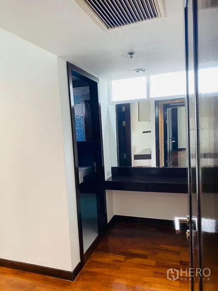 公寓 出租在Watthana, Bangkok - 过道转角设有台面与镜子，旁边为卫浴，木地板铺设。