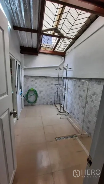 Townhouse for rent or sale in Suan Luang, Bangkok - Covered utility area with skylight roof, tiled walls, and floor drain.