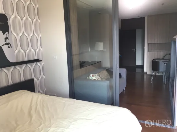 Condominium for rent in Khlong Toei, Bangkok - View from the bedroom through the sliding glass wall to the living room with built-in cabinetry.