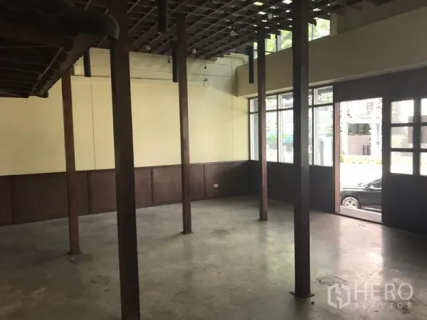 Retail Space for rent in Khlong Toei, Bangkok - Open-plan retail interior with timber columns, concrete floor, grid ceiling and street-facing windows near BTS Thong Lo.