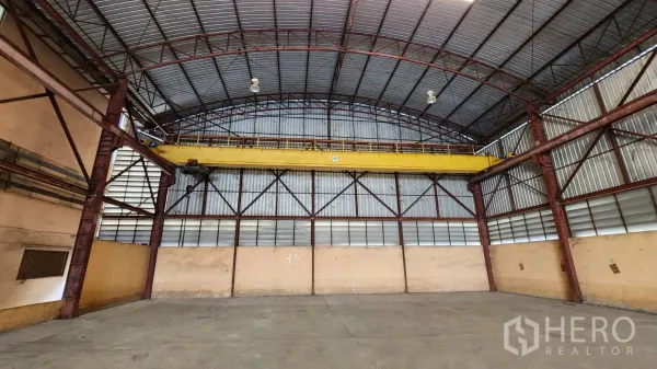 Warehouse for rent in Nonthaburi - End wall of the warehouse showing a yellow overhead crane and steel frame.