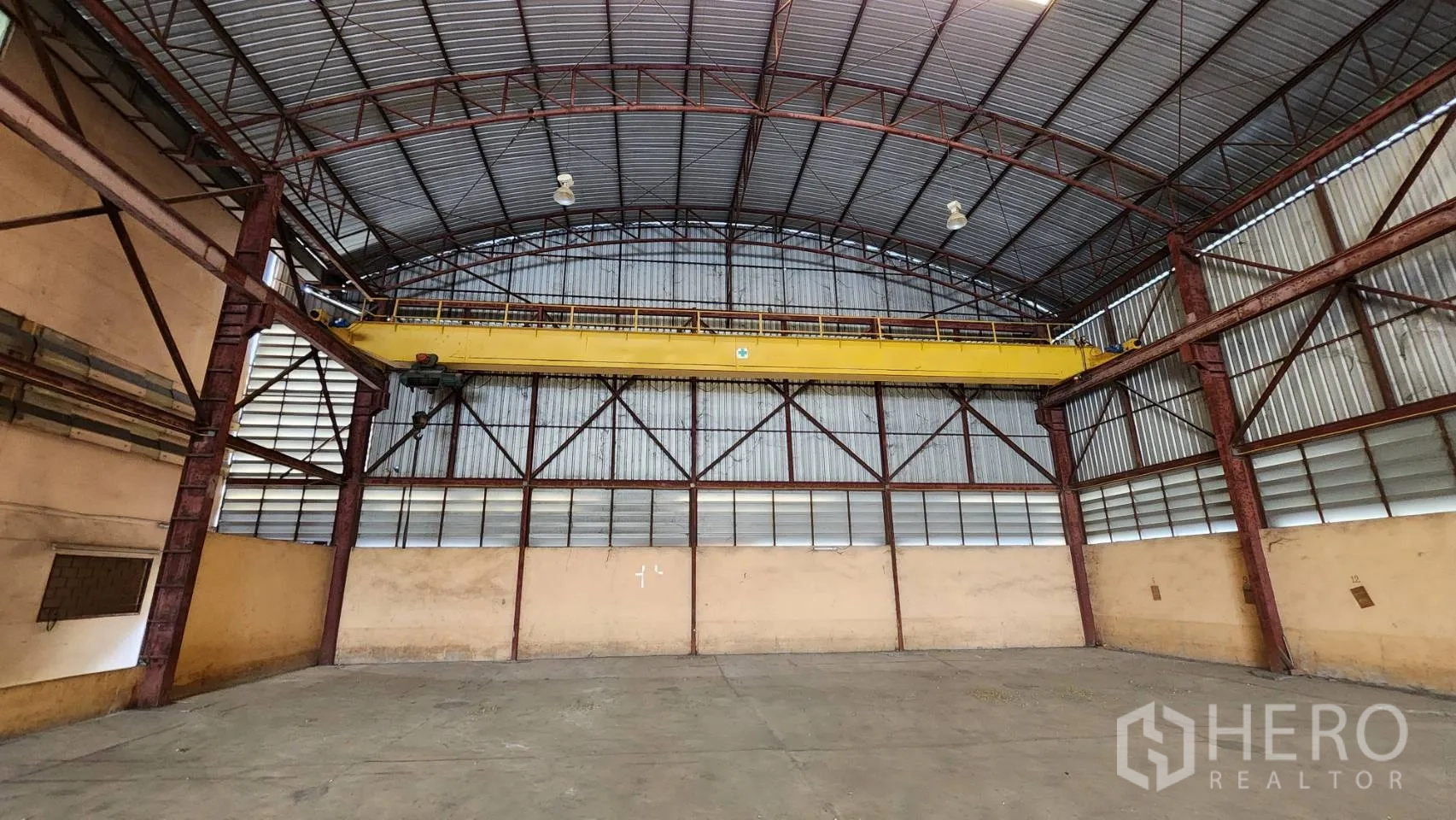 Warehouse for rent in Nonthaburi - End wall of the warehouse showing a yellow overhead crane and steel frame.