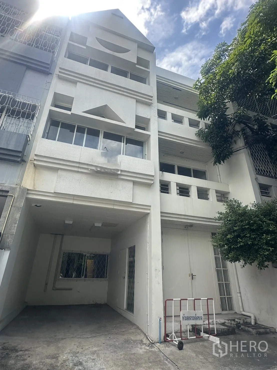 Home Office for rent in Watthana, Bangkok - Four-story white townhouse home office facade with covered carport and balcony openings.