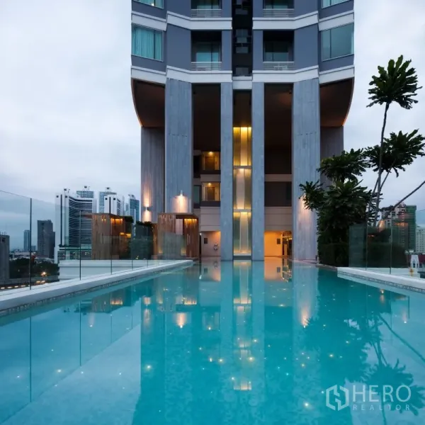 公寓 出租在Watthana, Bangkok - 公寓无边际泳池，玻璃护栏与城市天际线景观。