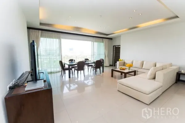 Condominium for rent in Sathon, Bangkok - Spacious lounge with L-shaped sofa, dining set and wide balcony windows.