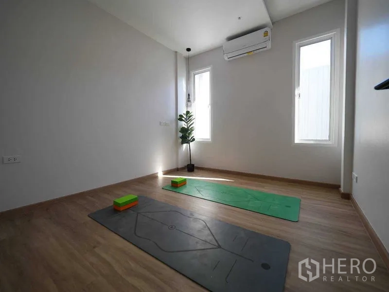 Townhouse for rent in Watthana, Bangkok - Flexible room set up as a yoga studio with two mats, wood floors and tall windows.