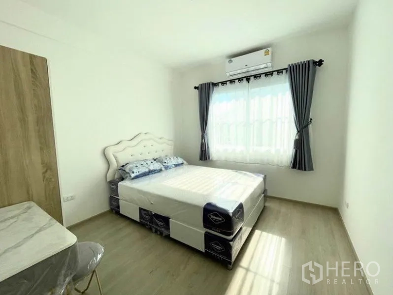 联排别墅 for rent in Prawet, Bangkok - 第二卧室配床、衣柜、书桌与带窗帘的窗户。