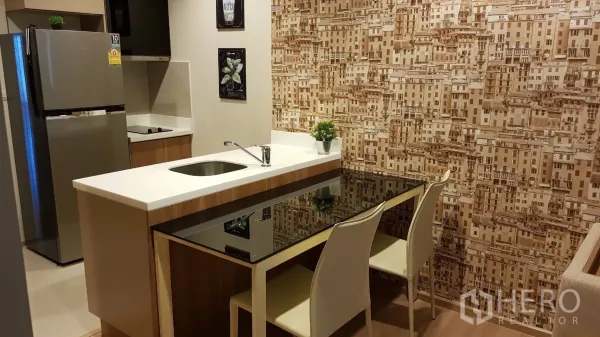 Condominium for rent in Sathon, Bangkok - Compact kitchen with island breakfast bar, sink, cooktop and stainless-steel refrigerator against a patterned wall.