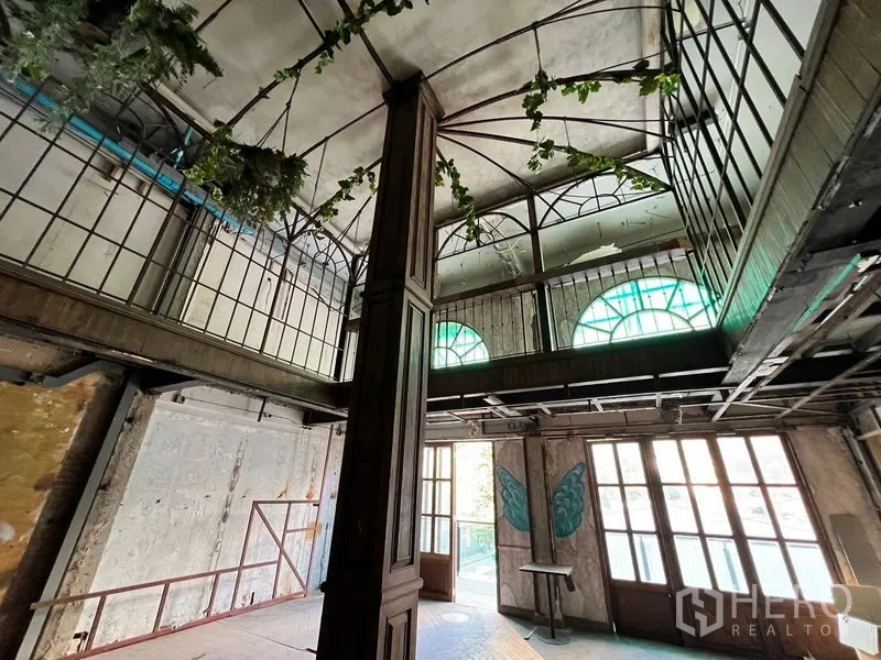 Shophouse for rent in Watthana, Bangkok - Loft-like interior with arched clerestory windows, balcony walkway, and rustic finishes.
