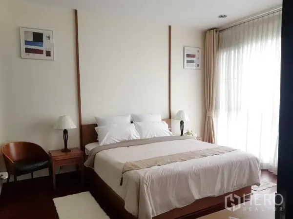 คอนโด ให้เช่าในPathum Wan, Bangkok - ห้องนอนหลักเตียงคิงไซส์ โต๊ะหัวเตียงและโคมไฟ พร้อมผ้าม่านทึบสูง