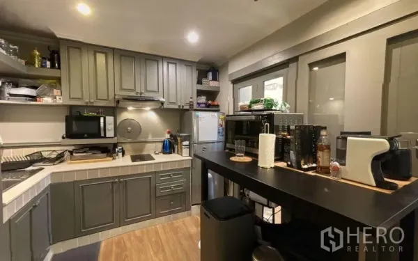 公寓 出售在Watthana, Bangkok - 现代灰色厨房，内置柜体、灶台、吧台与多种电器。