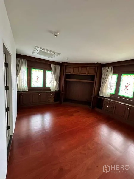 Condominium for rent in Bangkok - Cozy bedroom with wood cabinetry and stained glass-style windows.