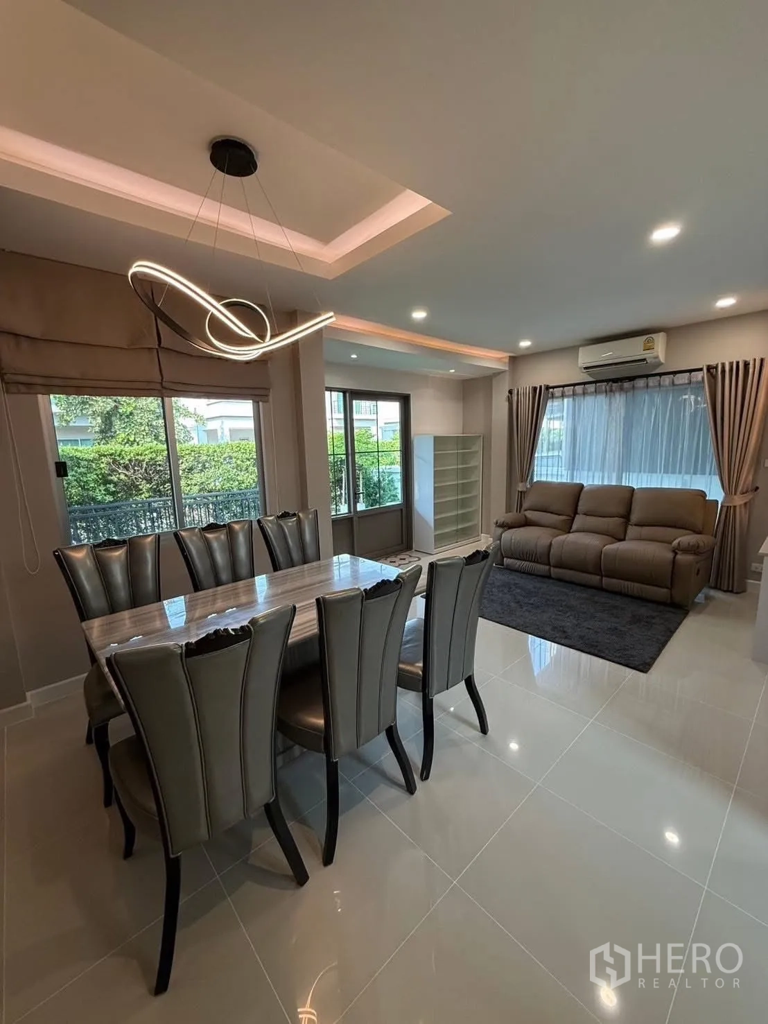 独栋房屋 for rent in Prawet, Bangkok - 餐区配造型吊灯，连接明亮客厅与花园景观