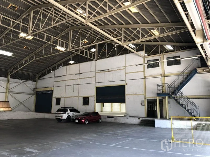 货栈 出租在Mueang Samut Prakan, Samut Prakan - 宽阔仓库分区，保温墙体、卷帘门及通往办公区的楼梯。