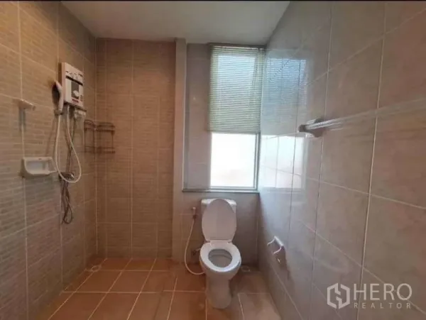 Townhouse for rent in Phra Khanong, Bangkok - Tiled bathroom with electric shower, toilet and a window with blinds.