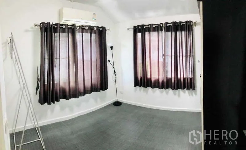 Detached House for rent or sale - Empty room with air conditioner and dark curtains on two windows.