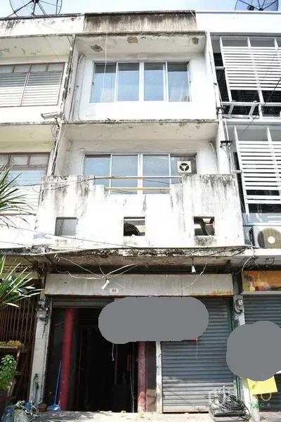Shophouse for rent in Khlong Toei, Bangkok - Four-storey shophouse exterior with balconies and roller shutters on a city row.
