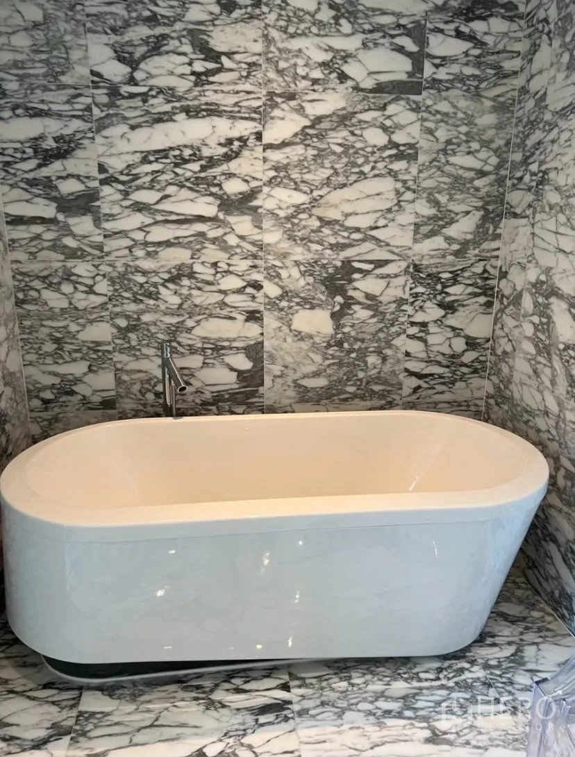 Condominium for rent or sale in Watthana, Bangkok - Freestanding bathtub set against marble wall and floor.