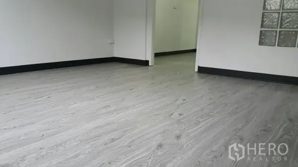 店屋 出租在Watthana, Bangkok - 浅灰木纹乙烯基地板与黑色踢脚线的近景。
