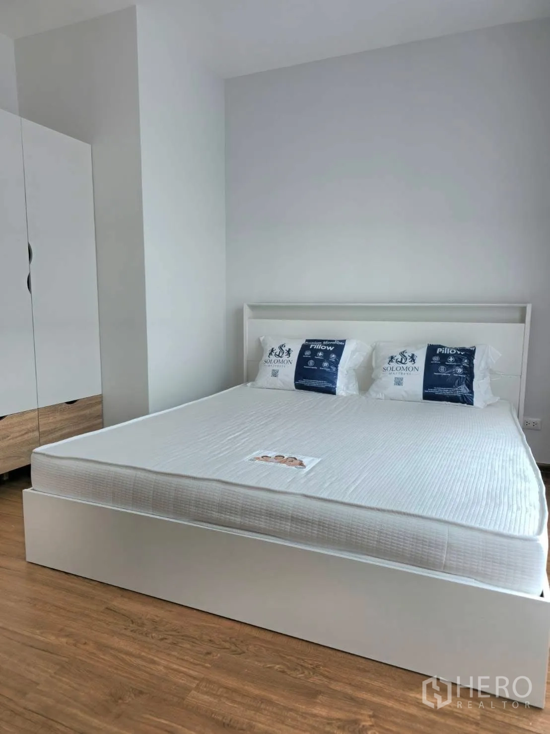 ทาวน์เฮาส์ for rent in Bang Phli, Samut Prakan - ห้องนอนหลักเตียงสีขาว ตู้เสื้อผ้า และพื้นลามิเนตลายไม้