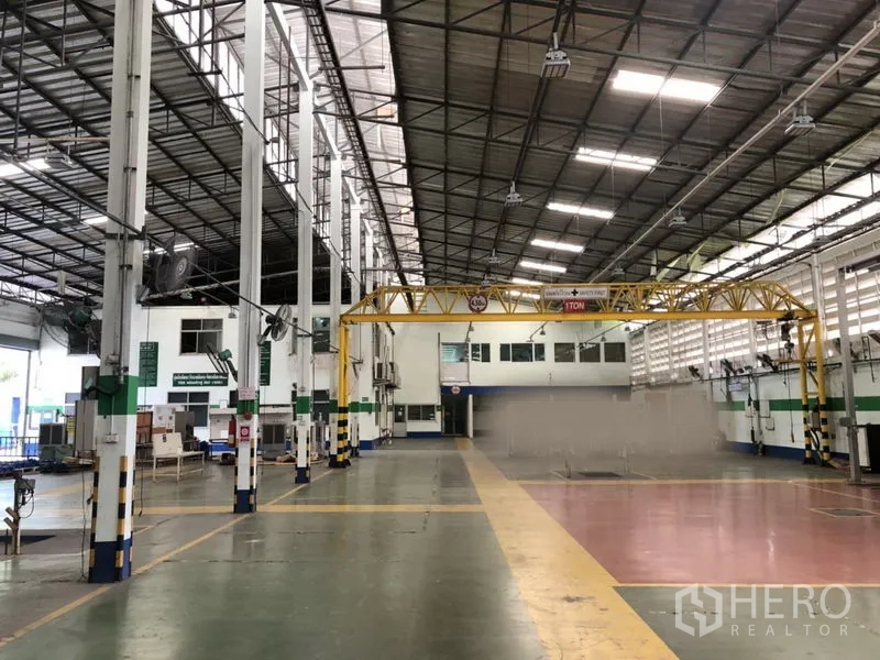 工厂 出租在Lam Luk Ka, Pathum Thani - 开阔生产车间，立柱高耸，侧墙通风良好，黄色门式行车靠近内部办公区。