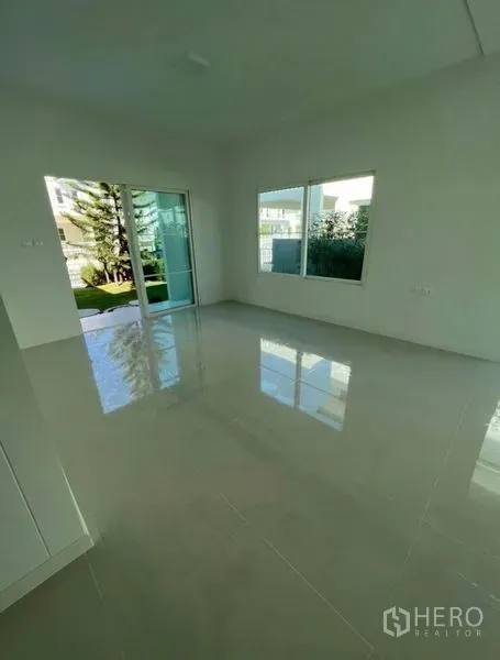 独立式住宅 出租在Min Buri, Bangkok - 明亮客厅，抛光地砖，大窗与推拉玻璃门通向花园，位于Min Buri独立屋内。