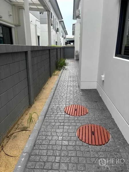 独立式住宅 出租在Mueang Nonthaburi, Nonthaburi - 侧边通道，压印混凝土路面与管线检修井盖。