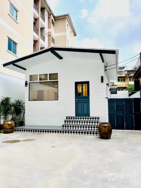 独立式住宅 出租 - 沙吞区白色独栋小屋正面，蓝色入户门与黑白棋盘格台阶。